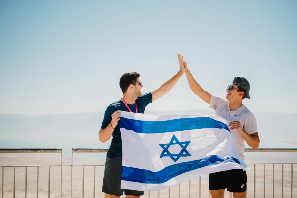 Two students high fiving holding an Israeli flag.