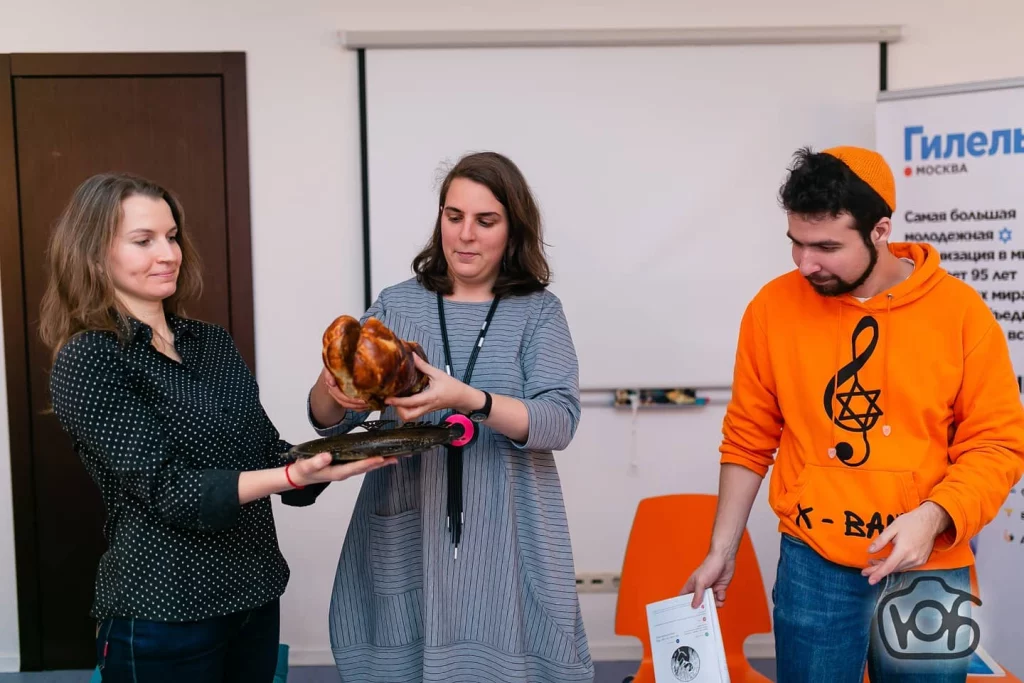 Group of three people, two of whom are holding two challot.