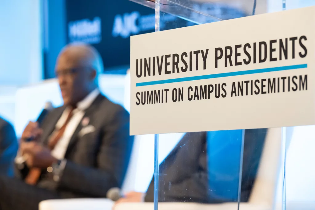 White sign with black text saying University Presidents Summit on Campus Antisemitism