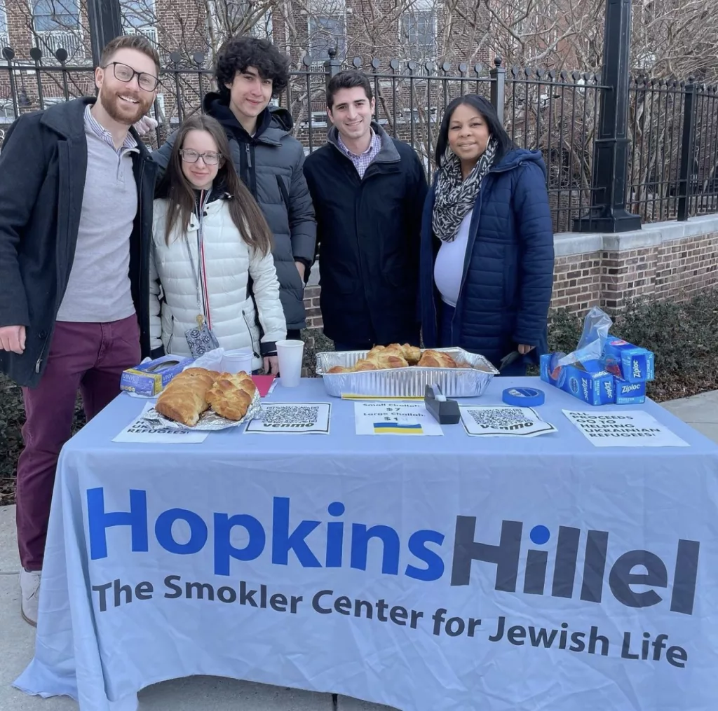 Students stand behind a Hopkins Hillel table