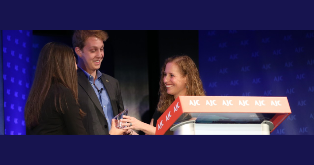 Three people hold an award behind a podium