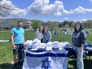 Students at UMass Amherst Hillel standing around a table with an Israeli flag
