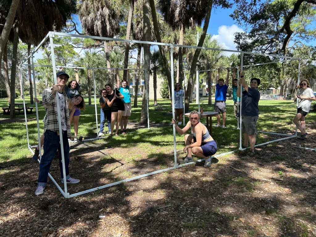 Students pose around a sukkah frame